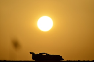 A sleek silhouette of a vintage 80s homologation special car against a sunset backdrop.