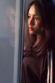 A woman with flowing hair, gazing thoughtfully out a window.