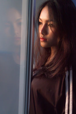 A woman with flowing hair, gazing thoughtfully out a window.