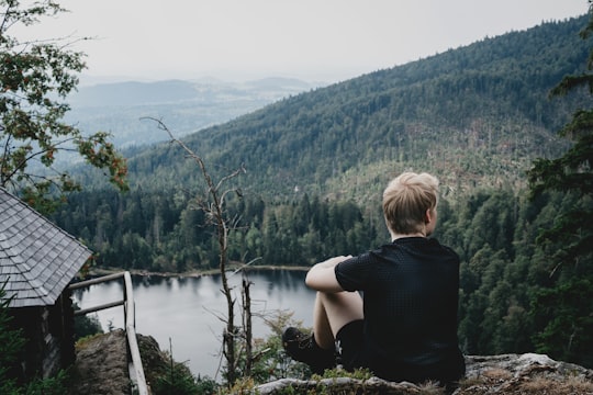 man sitting near house and body of water in Rachelsee Germany