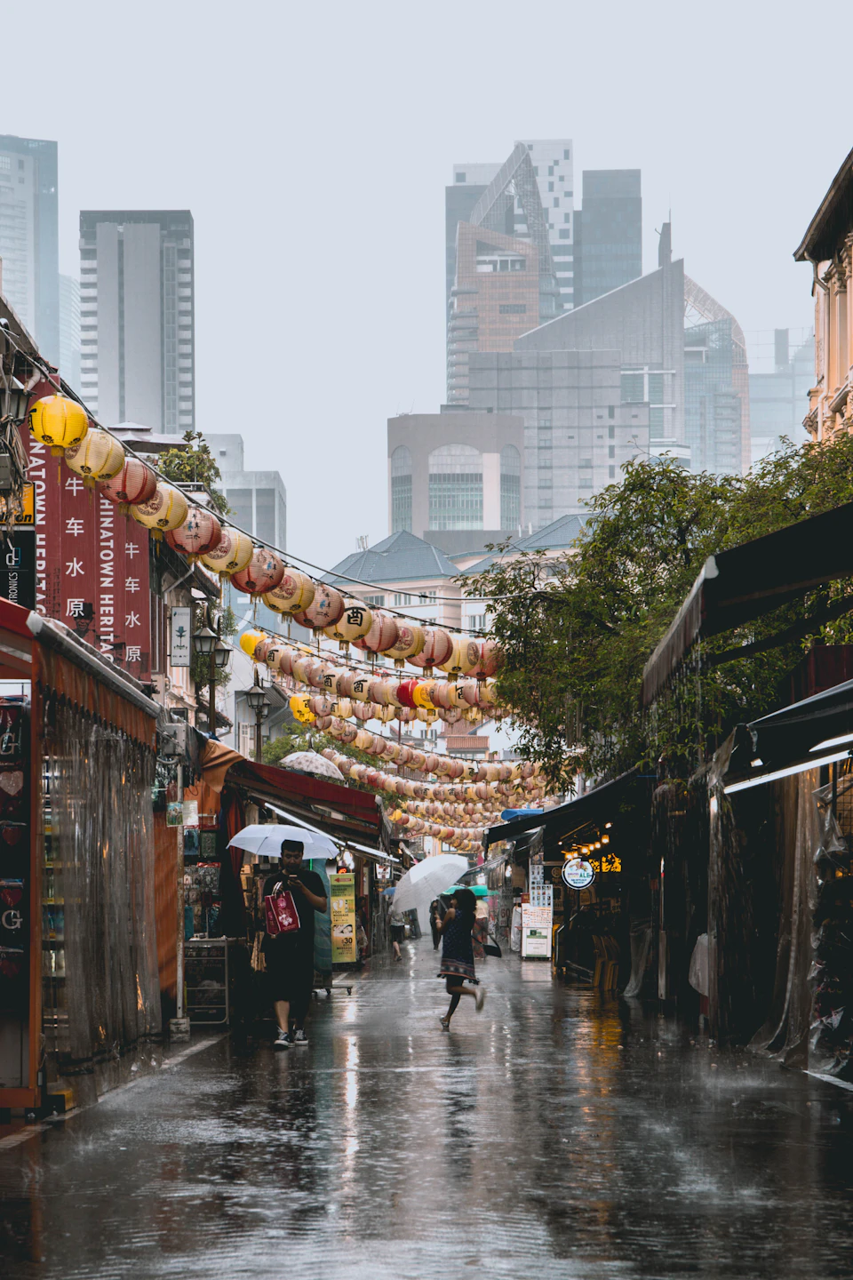 A person walking along a wet street beneath an umbrella during a tropical downpour