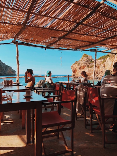 man and woman sitting on chair in front of table beside body of water