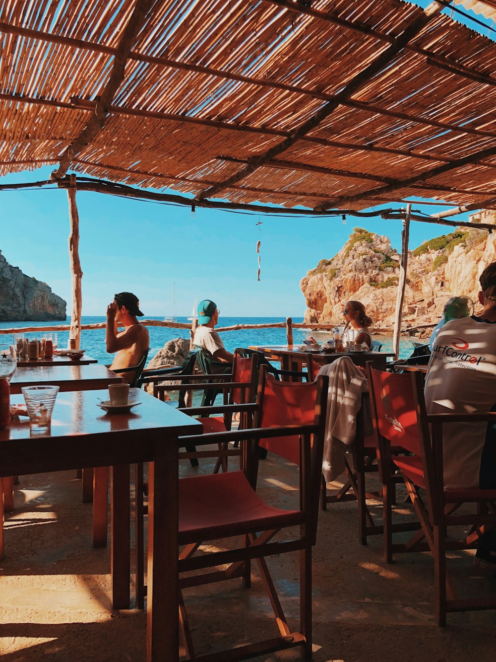 man and woman sitting on chair in front of table beside body of water