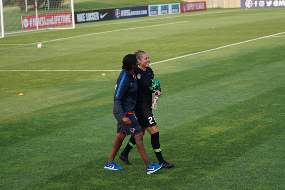 two female athletes walking side by side on sports field during daytime