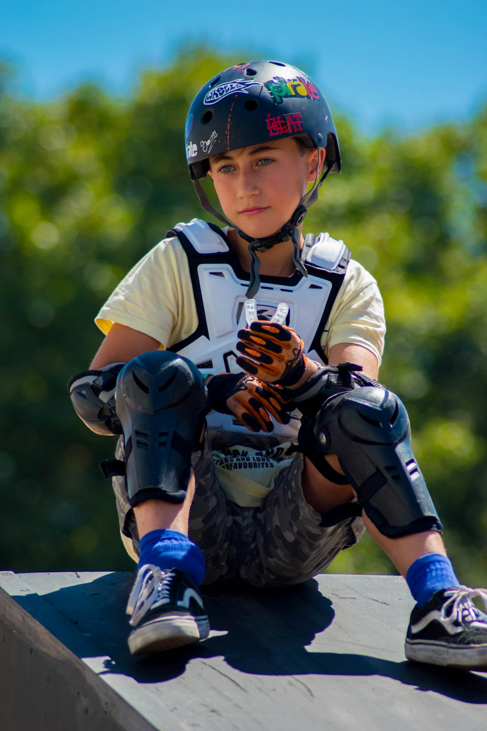 Niño en casco de bicicleta sentado en plataforma de madera gris