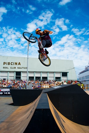 BMX rider riding above a set of ramps at an outdoor event with spectators watching