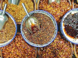 Fresh spices in wooden bowls arranged artfully on rustic fabric.