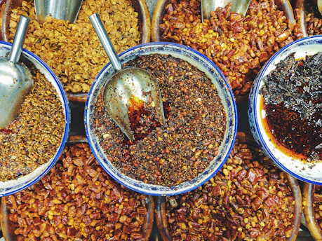 Colorful spices and dry fruits arranged in small bowls on a kitchen counter