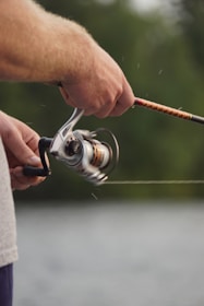 focus photo of man holding fishing rod and fishing reel