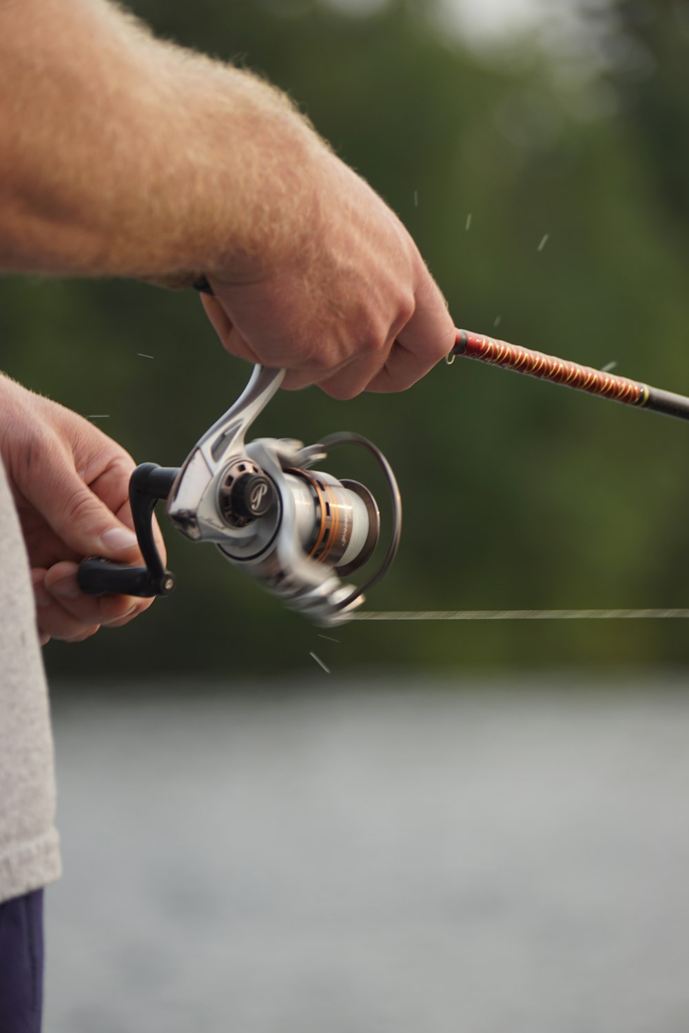 focus photo of man holding fishing rod and fishing reel