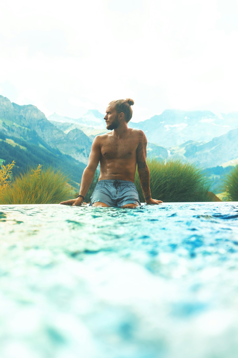 a man sitting in a pool with mountains in the background