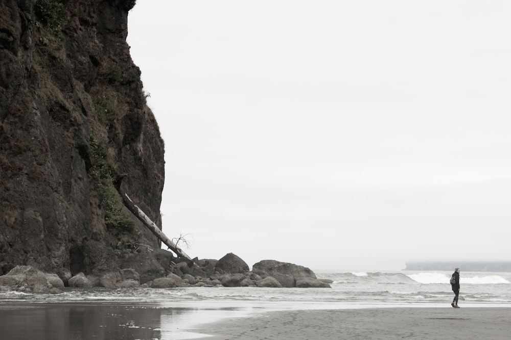 person standing behind mountain in front of large body of water during daytime