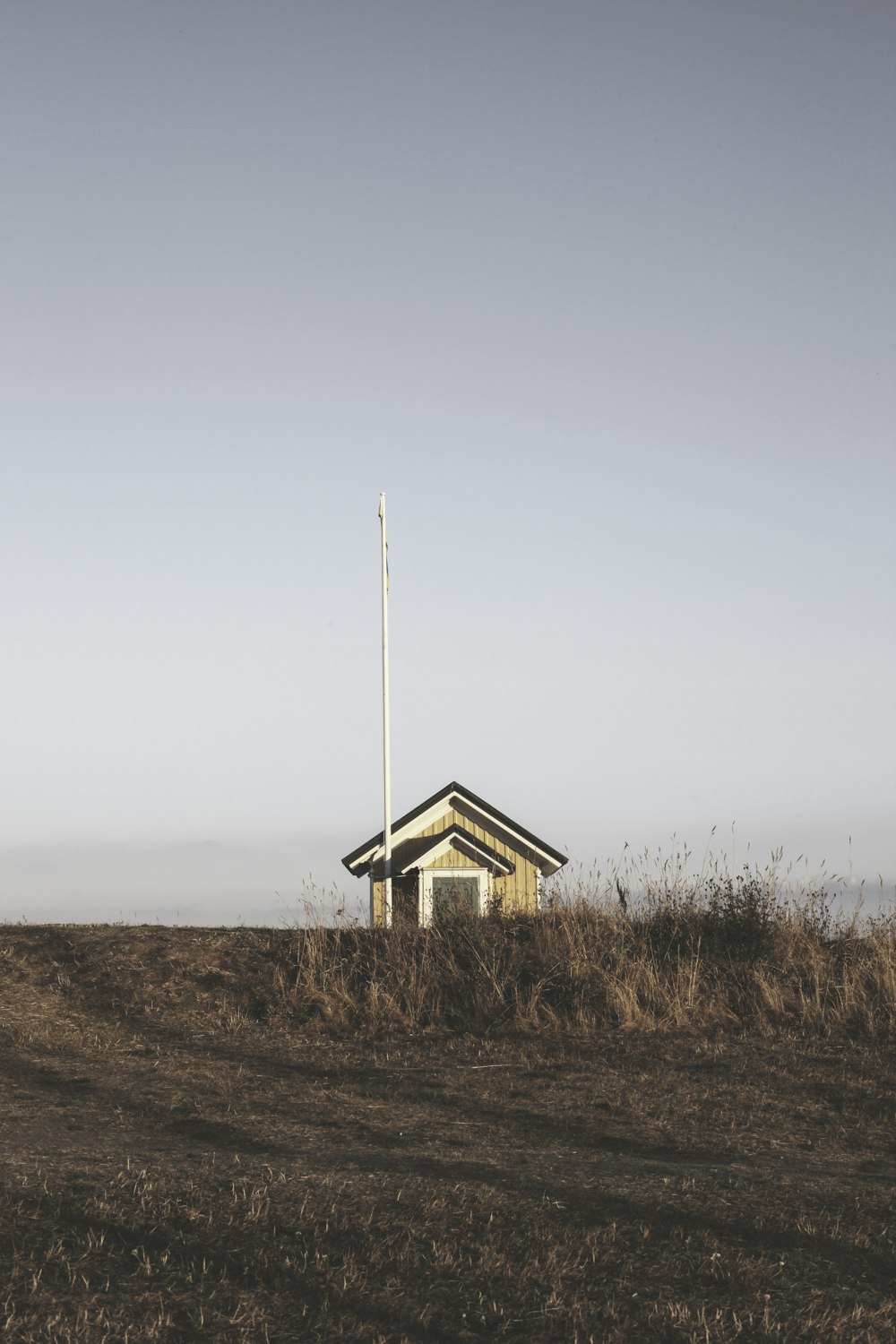 brown shed on field under gray clouds