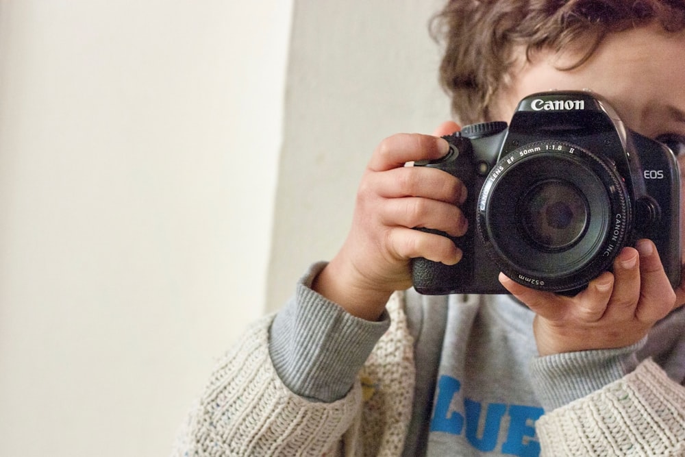 ragazzo che tiene la fotocamera reflex digitale Canon