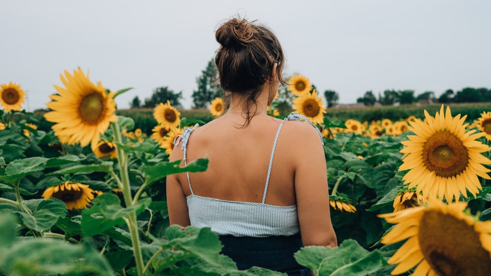 woman standing while surrounded by sunflower field