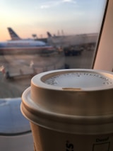 Close-up of hands comparing flight options on a digital tablet with a cup of coffee nearby.