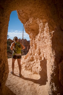 woman carrying backpack standing in cave passage
