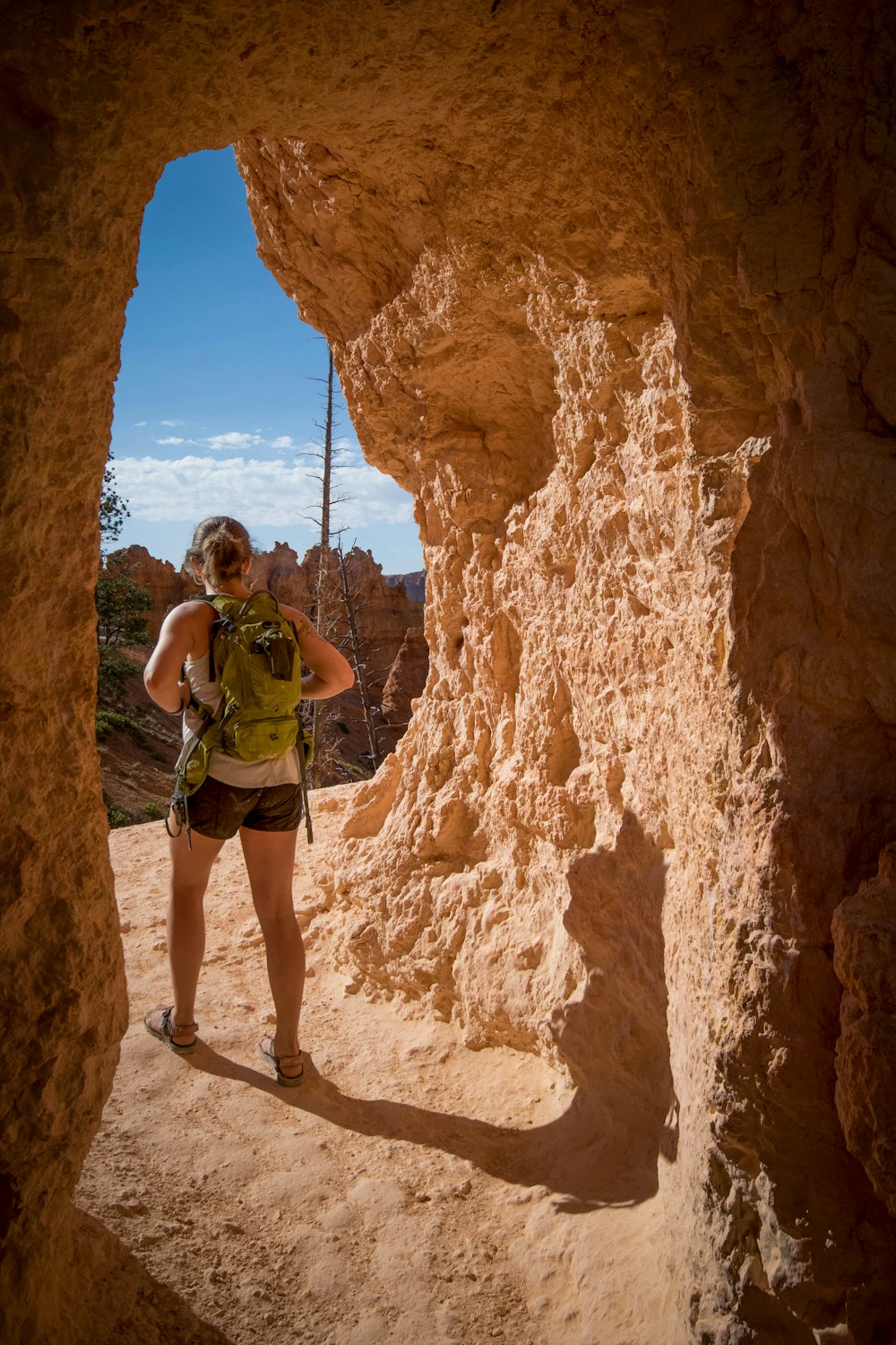 woman carrying backpack standing in cave passage