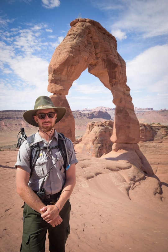 man standing near Delicate Arch in Arches National Park United States