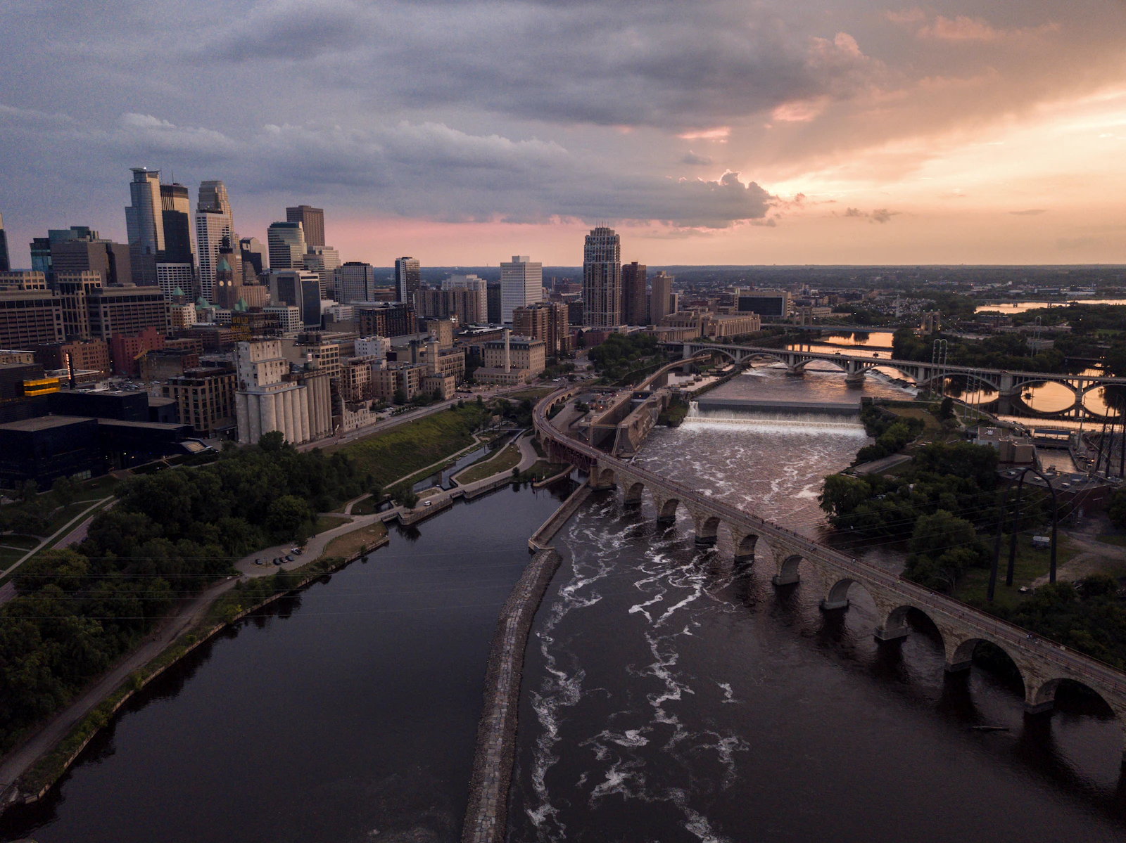 Downtown Minneapolis skyline with the Mississippi River and Stone Arch Bridge at sunset