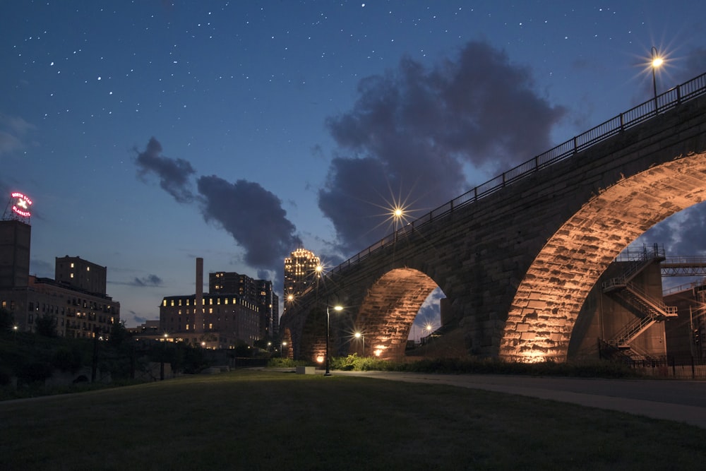 low-angle photo of brick bridge near buildings