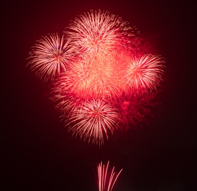 A festive scene with deep red fireworks lighting up the sky.