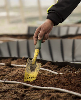 Gardener preparing soil with tools and fertilizer in a residential garden in Plovdiv