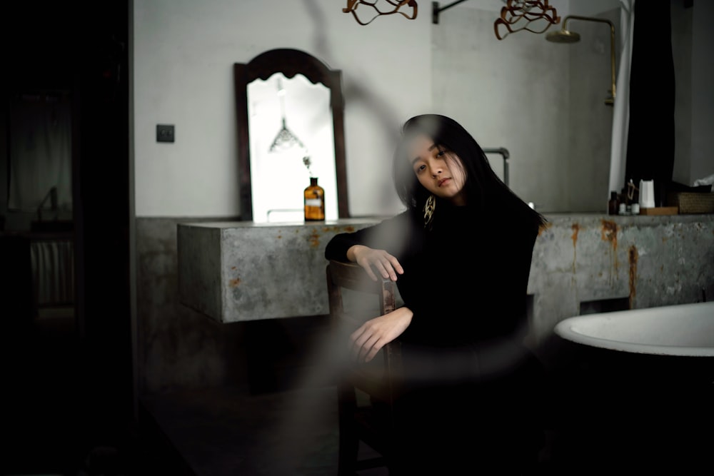 femme assise sur une chaise brune à côté d’une bouteille en verre brun à l’intérieur de la maison