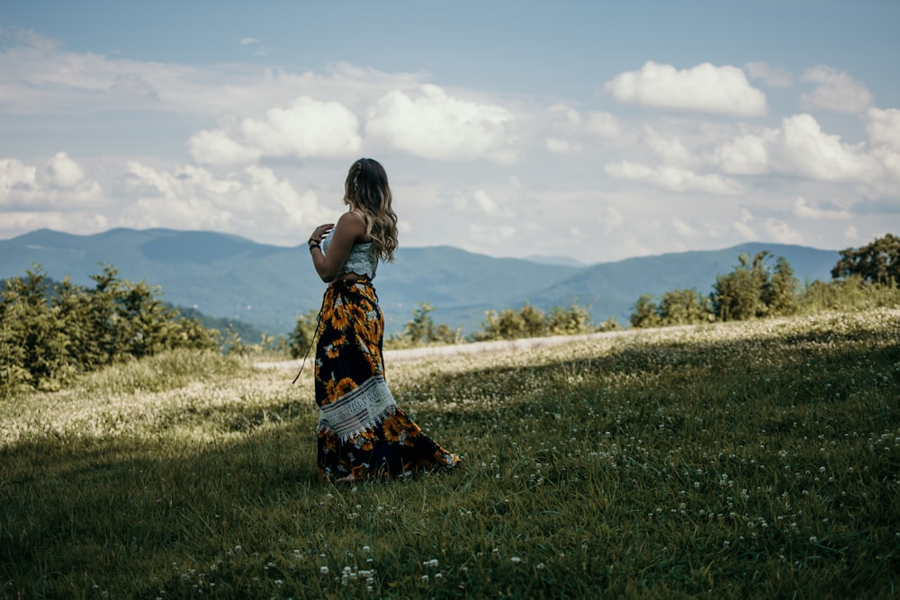 Donna in piedi sul campo di erba verde di fronte alle montagne