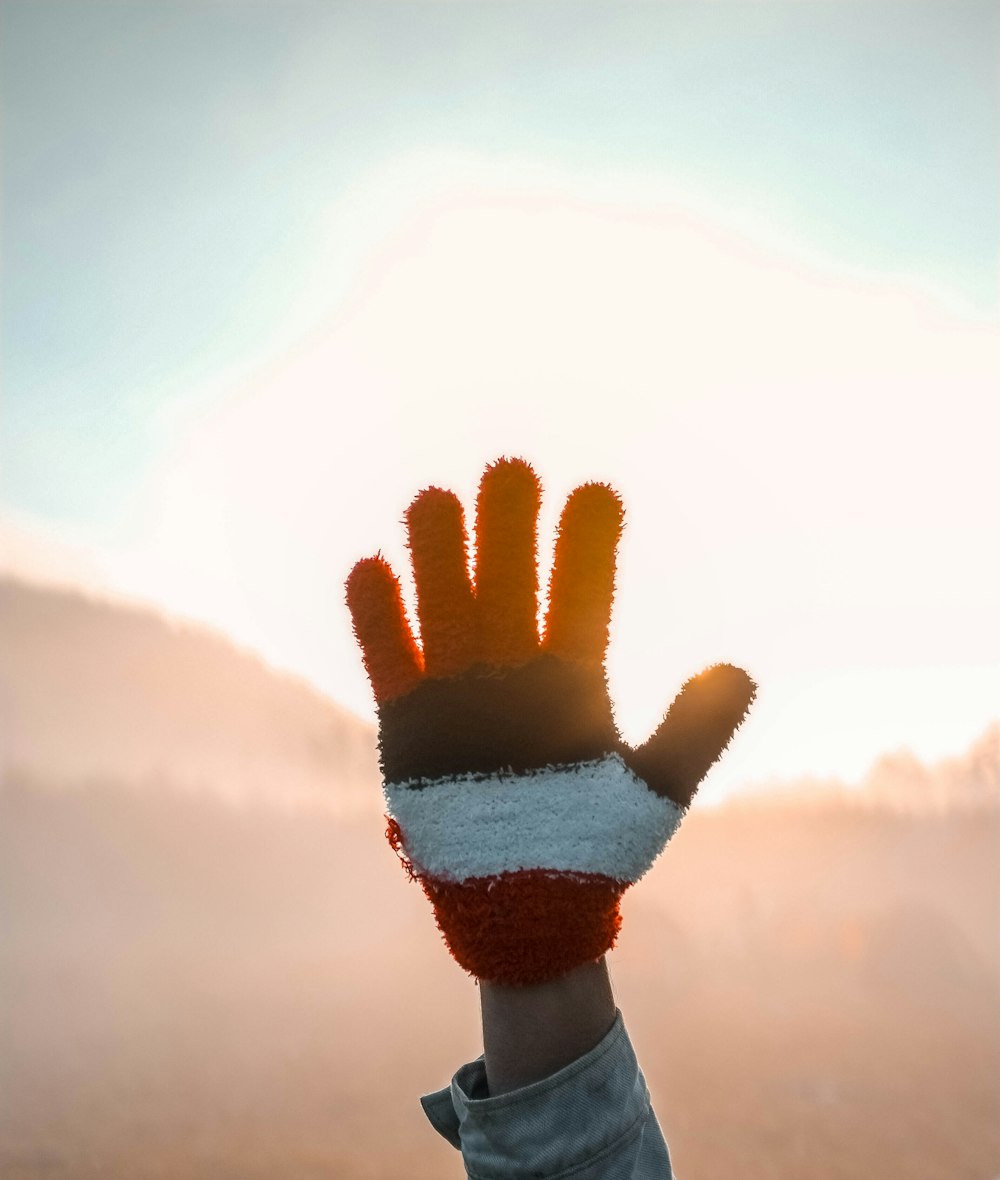 person wearing white, black, and red fleece gloves