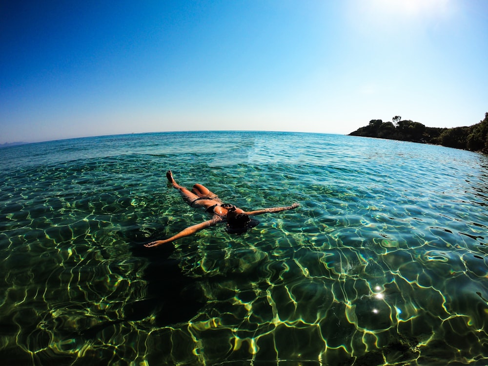 woman floating on body of water