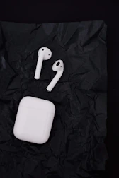 A pair of wireless earbuds resting on a charging case with a blurred background.