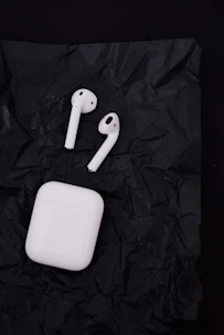 A pair of wireless earbuds resting on a charging case with a blurred background.