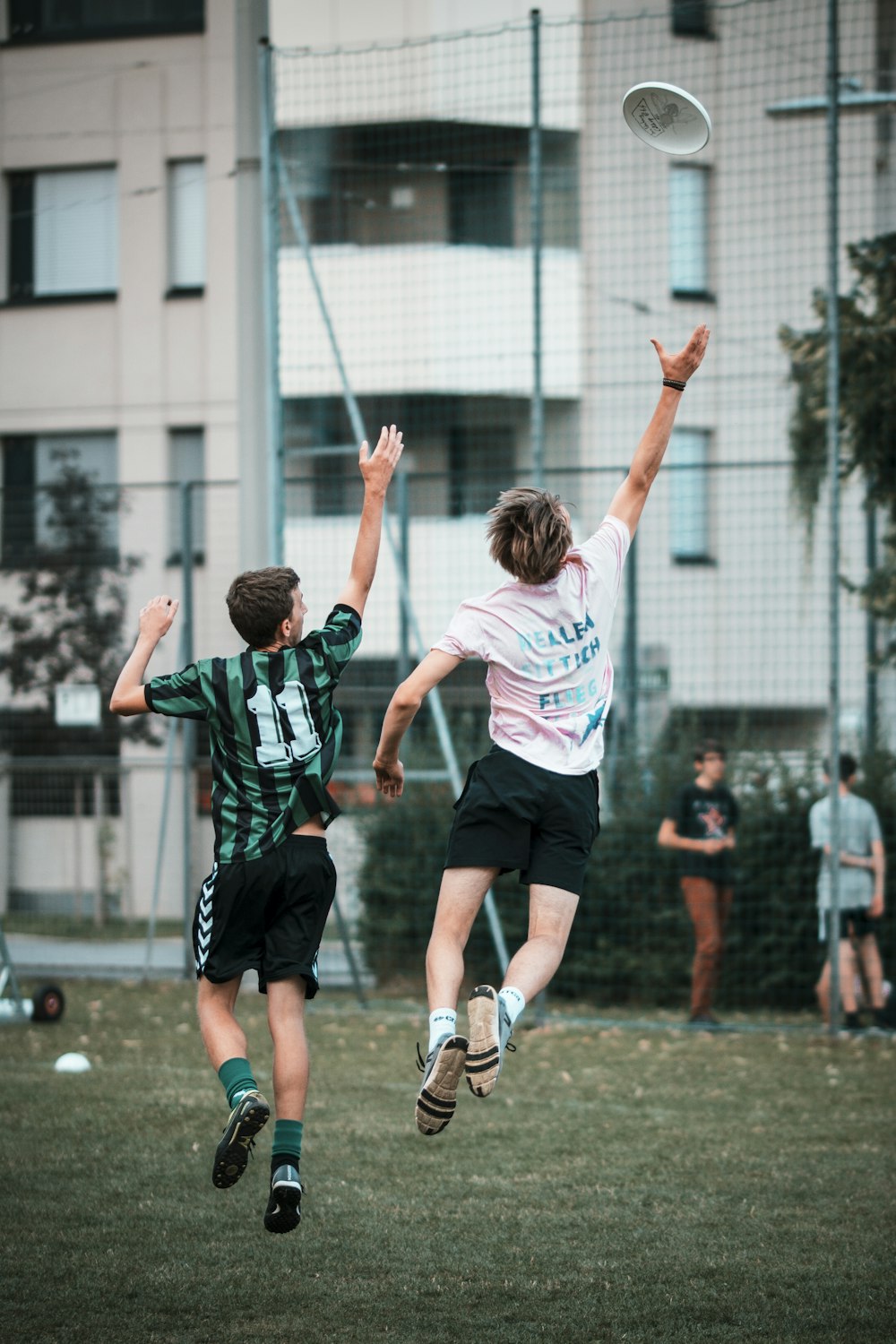 two men reaching frisbee while jumping