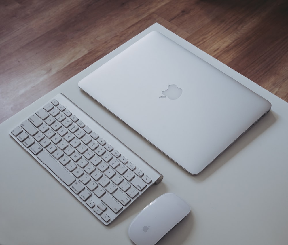 흰색 표면에 Apple Magic Keyboard 및 Apple Magic Mouse 근처의 은색 MacBook