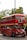 A classic red double-decker bus with signage for a wedding party is parked on a street. The bus is decorated with ribbons and has a sign that reads '2018 Happy Wedding Day' above the windshield. It is surrounded by greenery and trees in the background.