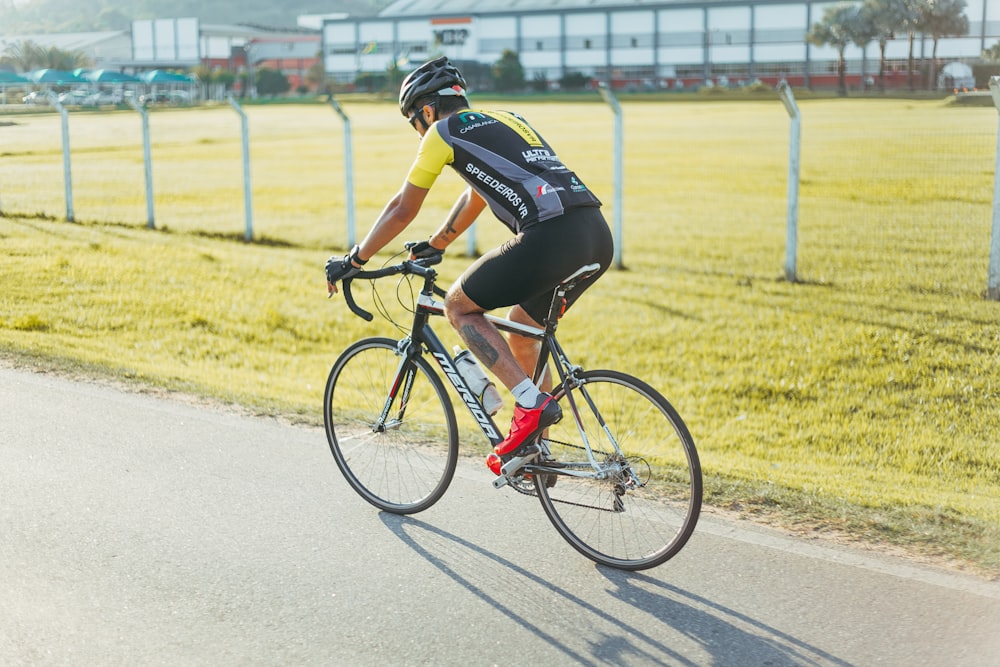 man riding on road bike near fence