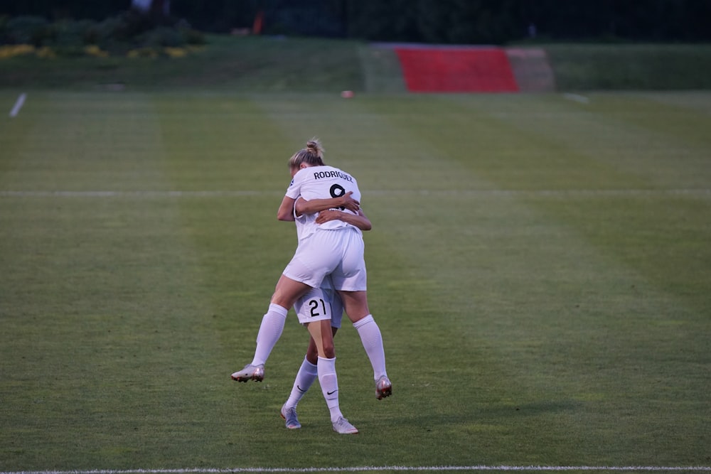 woman hugging her co player on green field