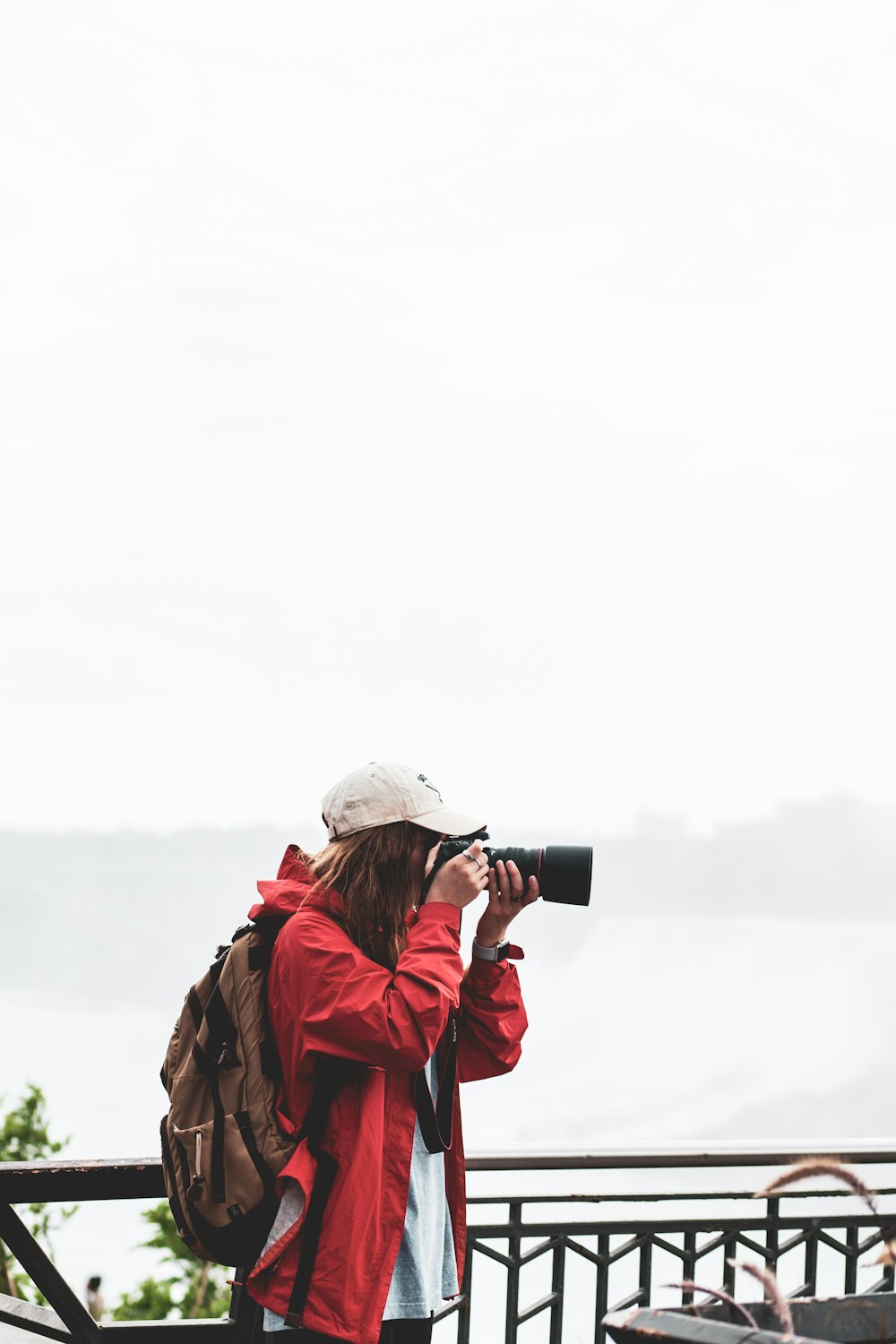 personne tenant un appareil photo reflex numérique noir prenant une photo pendant la journée