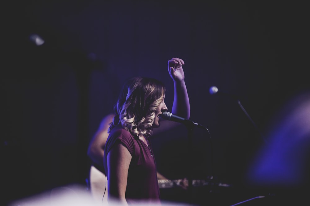 woman singing using microphone on stage