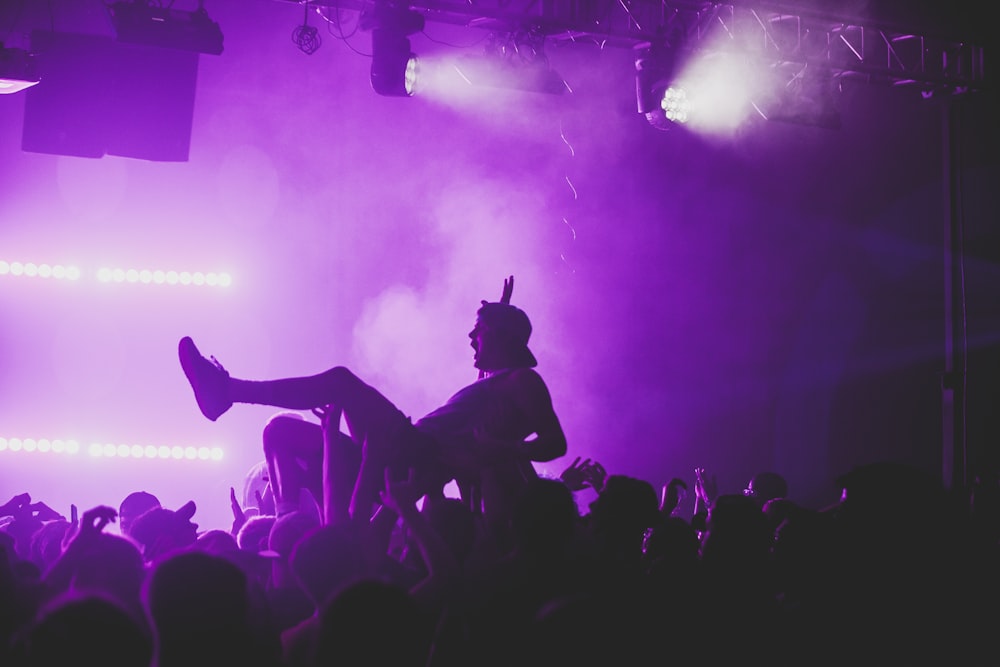 silhouette photo of man jumped off on top of people inside party hall