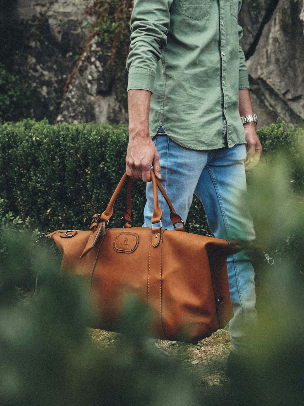 man holding bag near grass