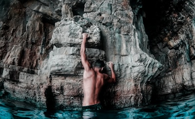 A climber scaling a rock wall in a natural outdoor setting.