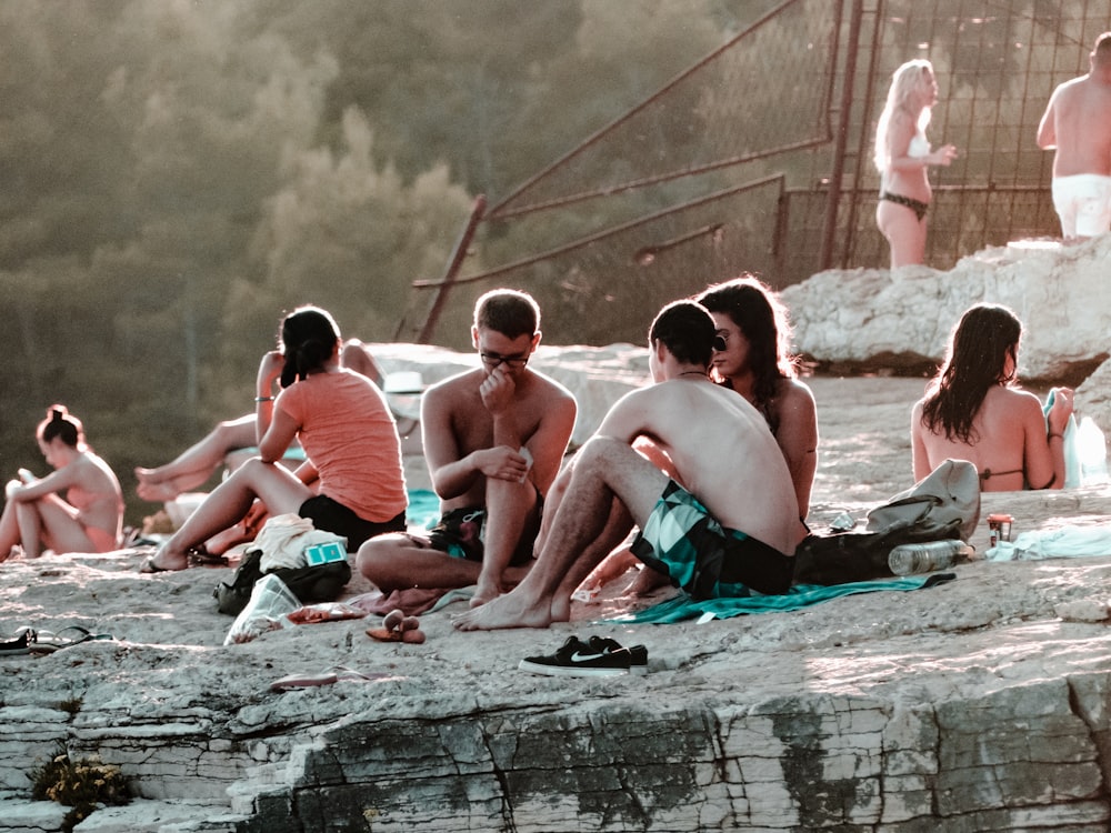 men and women sitting on top of a mountain cliff