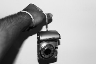 Hands holding a compact camera case against a neutral background.