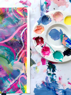 A vibrant painting in progress, with bold brush strokes and a palette full of rich colors nearby.