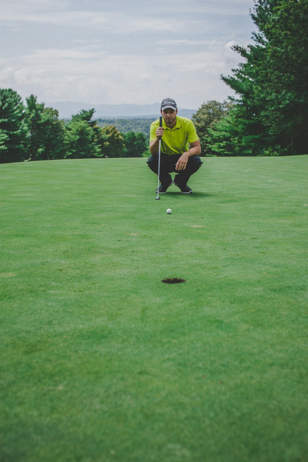 man playing golf sitting beside trees