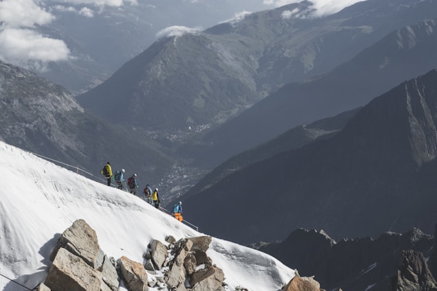 A group of climbers ascending a rocky mountain peak during sunrise.