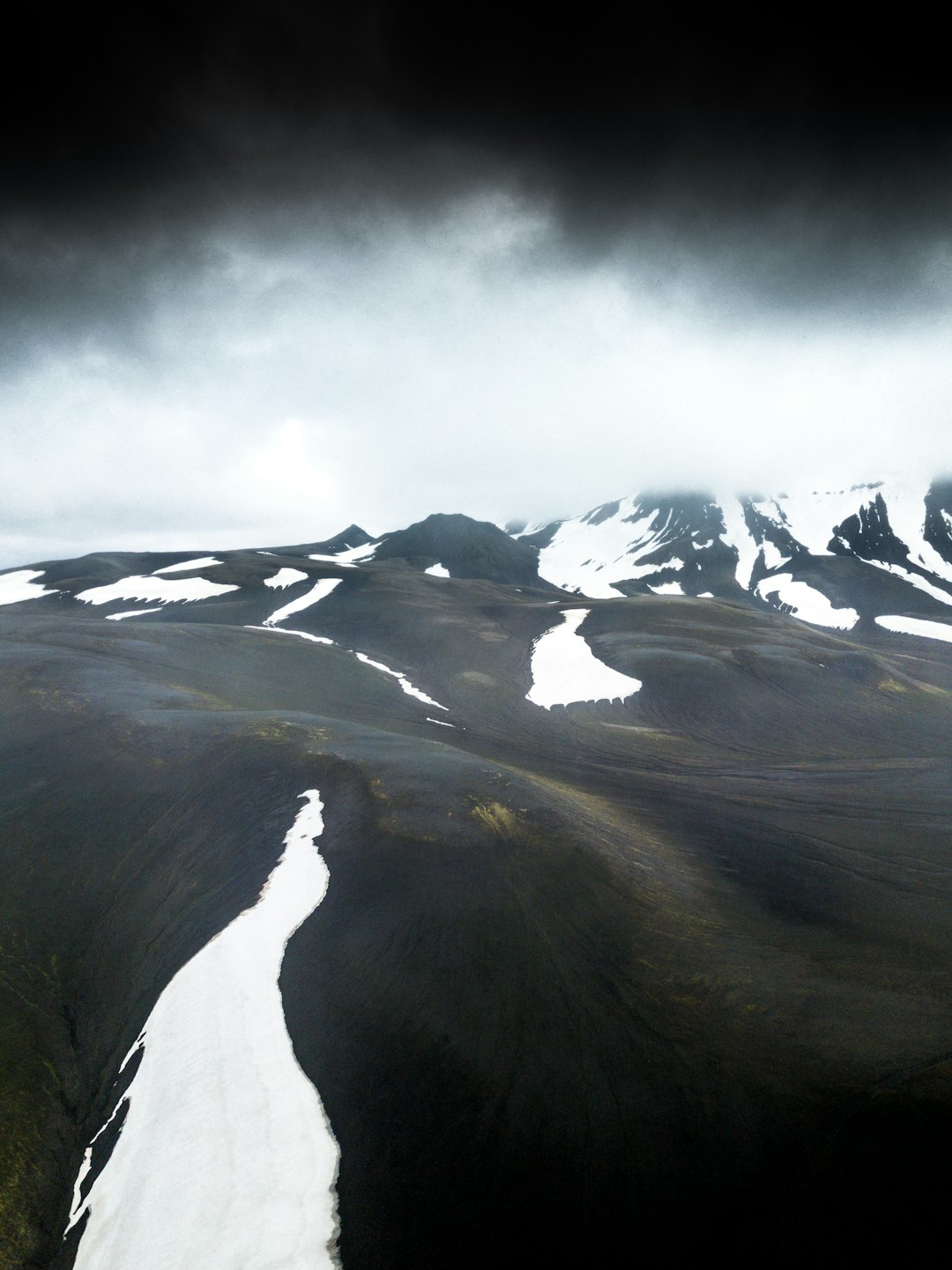 snow capped mountain under dark clouds