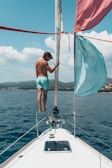 man standing on rail of boat